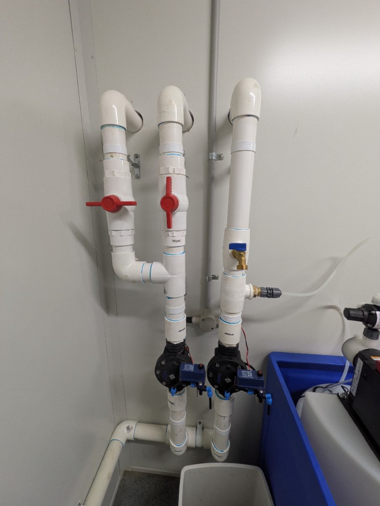 Distribution manifold in the WWTP control room — manual LAA valves and Netafim solenoids