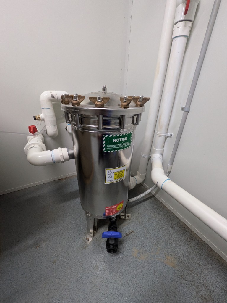 Harmsco stainless-steel microfilter in the WWTP control room, with isolation and blue flush valves